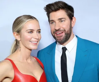 A woman in a red dress and a man in a blue suit smiling at an event.