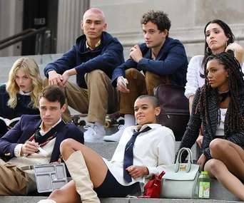 Group of young people sitting on steps in stylish outfits, representing diverse characters from the Gossip Girl reboot.