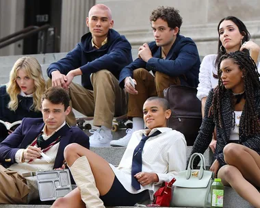 Group of young people sitting on steps in stylish outfits, representing diverse characters from the Gossip Girl reboot.