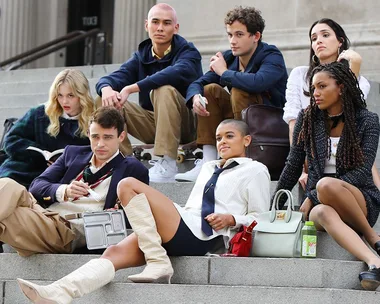 Group of stylish young people sitting on steps, representing characters from the Gossip Girl reboot.