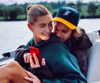 A couple sitting closely on a boat, with the woman holding a red phone, smiling.