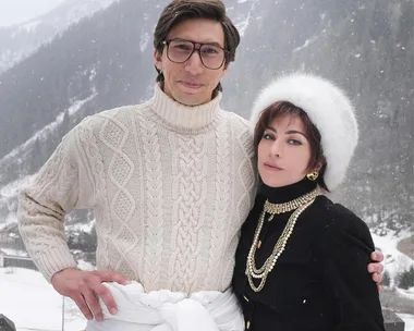 Two characters from "House of Gucci" in winter attire, posing in a snowy mountain setting.