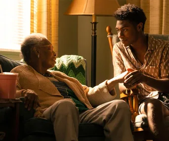 Elderly person and young man sharing a heartfelt moment in a cozy living room setting.