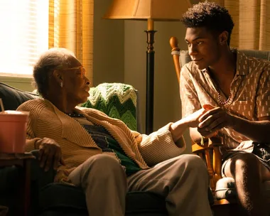 Elderly person and young man sharing a heartfelt moment in a cozy living room setting.