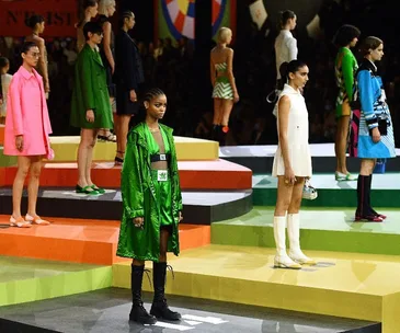 Models on a colorful tiered stage wearing vibrant outfits from Dior's Spring/Summer 2022 collection.