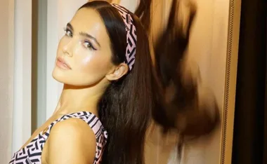 Woman in patterned dress and matching headband with sleek hairstyle at a Met Gala after-party.