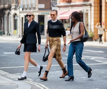 Three stylish individuals crossing the street during London Fashion Week 2021, showcasing diverse trends and outfits.