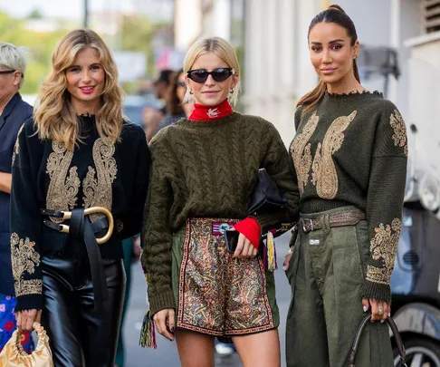 Three women in stylish embroidered outfits at Milan Fashion Week 2021, smiling and posing on the street.