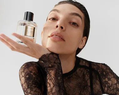 Person in lace top holds a bottle of Glasshouse fragrance titled "A Tahaa Affair."