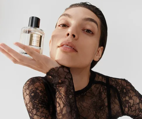 Person in lace top holds a bottle of Glasshouse fragrance titled "A Tahaa Affair."