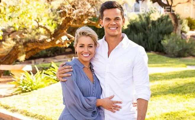 A couple smiling and embracing in a sunny garden setting from The Bachelor Australia.