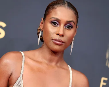 Issa Rae at the 2021 Emmys, wearing elegant earrings and a sparkling gown with vivid purple eye makeup.