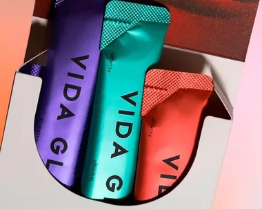 Packets of Vida Glow collagen supplements in a box, featuring blue, green, and red packaging.