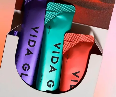 Packets of Vida Glow collagen supplements in a box, featuring blue, green, and red packaging.