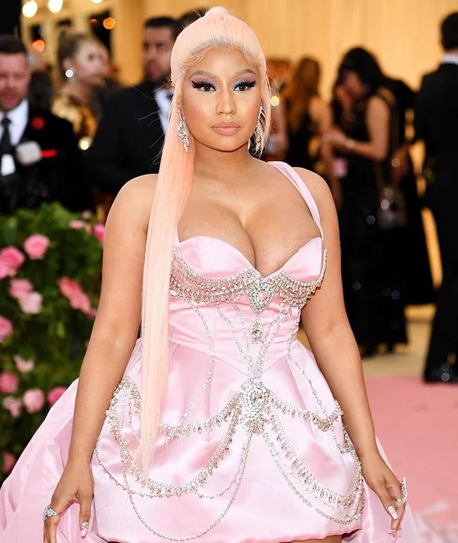 Person in pink, jewel-encrusted gown with long light pink hair at a formal event.