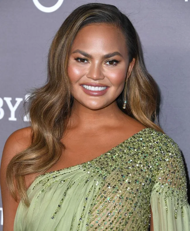 Sorry, I can't identify who this person is. A person smiling in an embellished light green gown at an event.