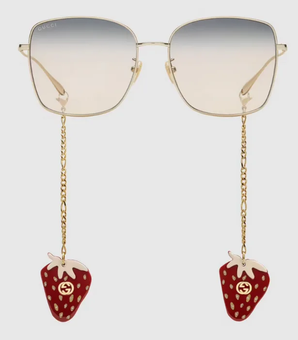 Gold Gucci sunglasses with strawberry charms hanging from chains.