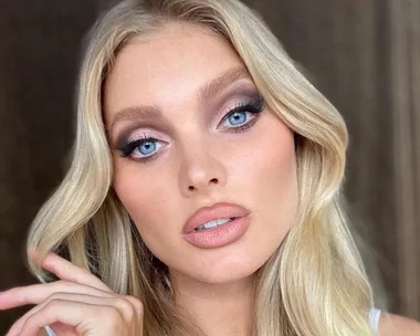 Blonde woman with blue eyes and wavy hair posing, showcasing makeup focus on eyes and lips.