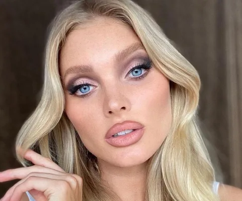 Blonde woman with blue eyes and wavy hair posing, showcasing makeup focus on eyes and lips.