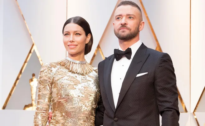 Elegant couple in formal attire walking a red carpet event.