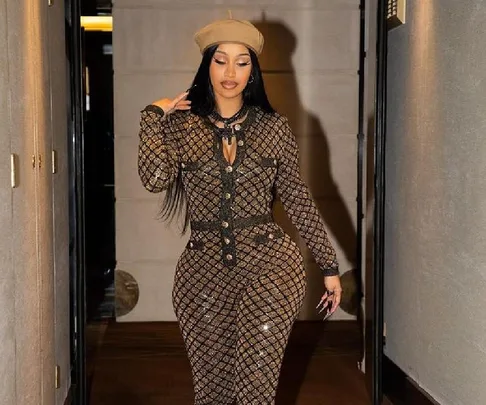 Woman in patterned jumpsuit and beret walking down a hallway.