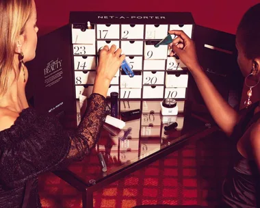 Two women opening drawers of the Net-A-Porter beauty advent calendar, with various beauty products visible.