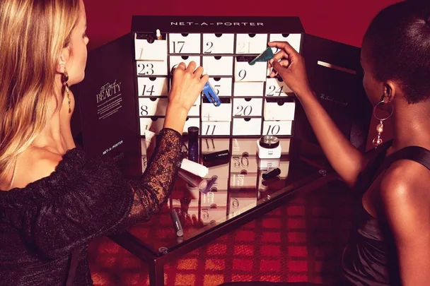 Two women opening drawers of the Net-A-Porter beauty advent calendar, with various beauty products visible.