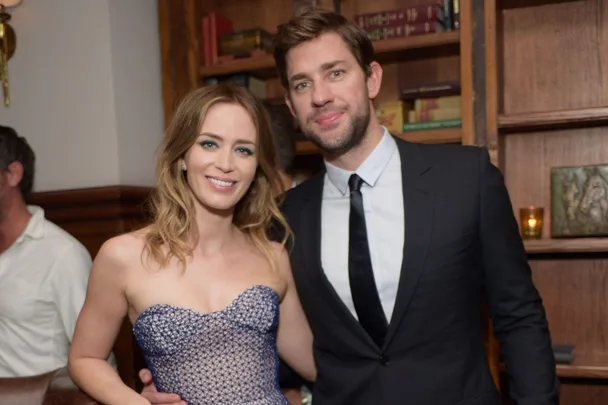 A couple posing together at a dinner event, wearing formal attire, with bookshelves in the background.