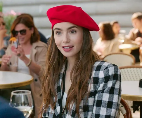 "Character from 'Emily in Paris' wearing a red beret and black-and-white checkered blazer, smiling at an outdoor café."