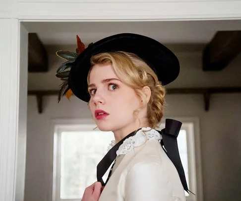 A woman in vintage attire with a decorative hat looks over her shoulder inside a bright room.