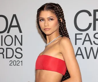 Woman in a red top with braided hair poses on the CFDA Fashion Awards 2021 red carpet.