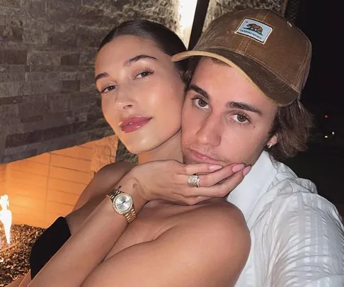 Two people pose closely for a selfie in front of a brick fireplace.