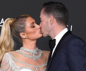 A couple sharing a kiss, with the woman in a jeweled gown and the man in a suit.