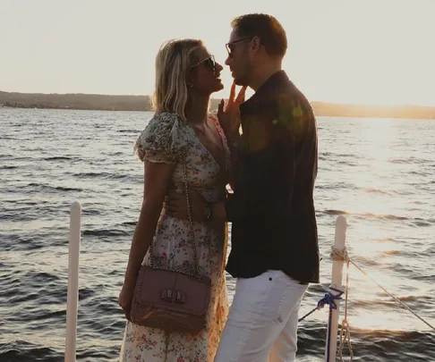 A couple in love embraces on a boat at sunset, with the ocean in the background.