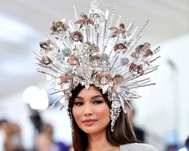 A person wearing an elaborate, sparkling headpiece with various textures and reflective elements at a formal event.