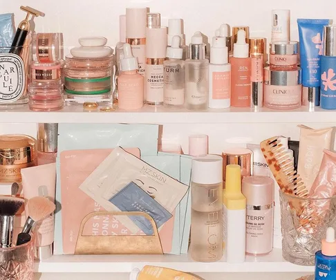 A neatly organized shelf filled with assorted skincare and beauty products including creams, serums, and brushes.