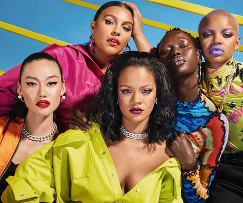 Diverse group of models in vibrant outfits and bold makeup, posing confidently against a colorful backdrop.