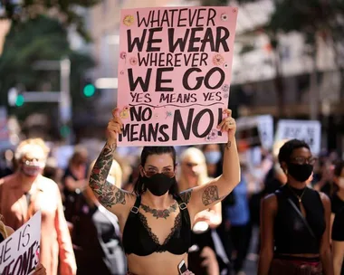 Protesters march holding signs advocating for affirmative consent laws, one reading "Yes means yes, no means no."