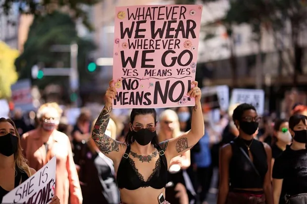 Protesters march holding signs advocating for affirmative consent laws, one reading "Yes means yes, no means no."