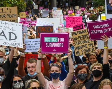 Protesters holding signs demanding justice for survivors, including "Justice for Survivors" and "Survivors Deserve Better."