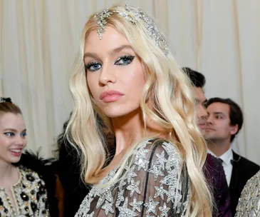 A person with platinum blonde hair and starry dress at an event, others in the background.