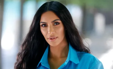 A woman with long dark hair wearing a bright blue shirt outdoors.