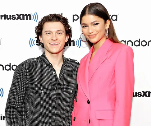 Two individuals smiling at a SiriusXM and Pandora event, one in a black polka dot shirt and the other in a pink blazer.