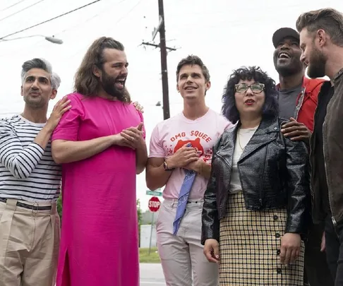 The Queer Eye cast stands with Sarah Lim, who is wearing glasses and a leather jacket, smiling outdoors.