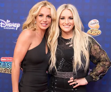 Two women posing together on a blue Disney Channel backdrop at an event.