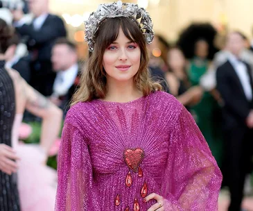 Person in a vibrant pink dress with heart detail and silver headpiece at a formal event.