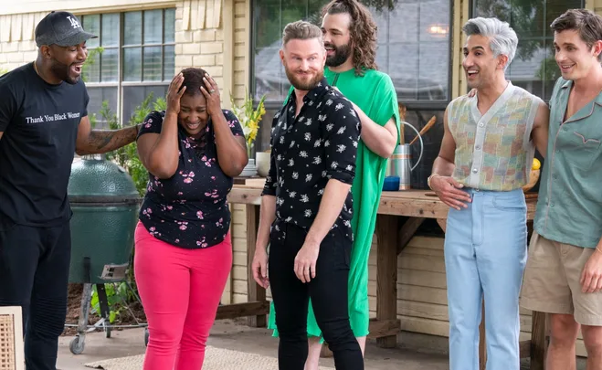 A joyful moment from "Queer Eye" featuring Jereka embraced by the Fab Five outside a house.