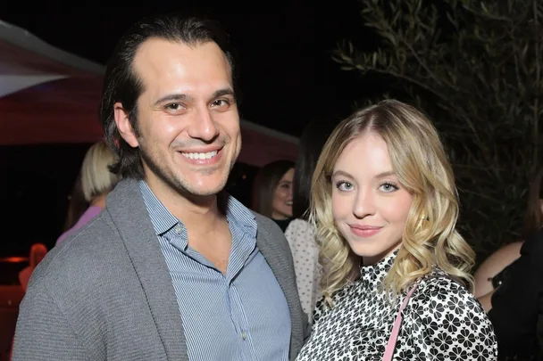 A smiling couple at a nighttime event, the woman has blonde hair and the man has dark hair.