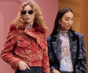 Two models showcase Zimmermann Fall 2022 collection; one in red print jacket, the other in blue blazer with graphic top.