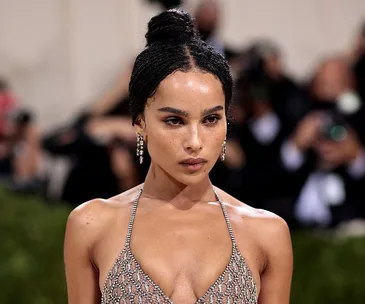 A woman wearing a shimmering, sleeveless dress with a high bun hairstyle at a fashion event.